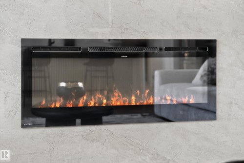 Wall-mounted electric fireplace with a black glass front and visible flame effect against a textured wall surface - 711 166 Avenue, Edmonton, AB - Indoor With Fireplace