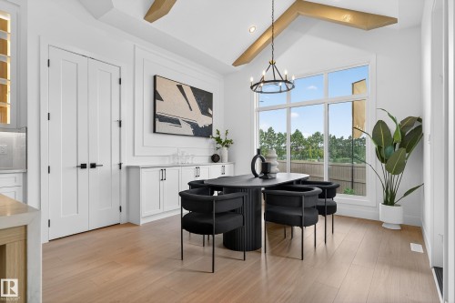 Dining area featuring a vaulted ceiling with exposed beams, wood-finish flooring, a wall of windows, and built-in cabinetry with a countertop - 711 166 Avenue, Edmonton, AB - Indoor