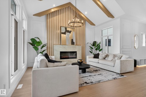 Vaulted ceiling with exposed wood beams, featuring a contemporary fireplace with a stone surround and linear firebox - 711 166 Avenue, Edmonton, AB - Indoor Photo Showing Living Room With Fireplace