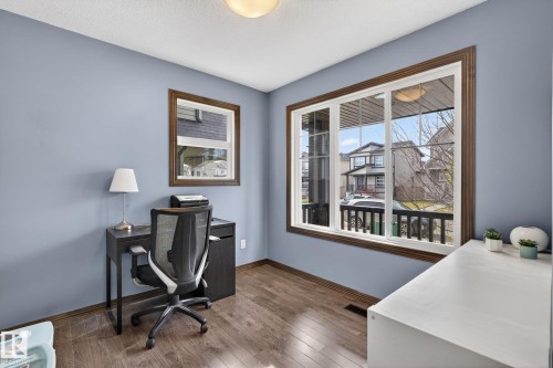 Room featuring wood-finish flooring, two windows with dark wood trim, and light blue walls - 108 Hewitt Circle, Spruce Grove, AB - Indoor Photo Showing Other Room