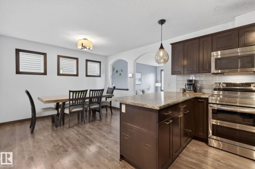 Kitchen featuring dark wood-finish cabinetry, stainless steel appliances, a light-toned countertop, and a subway tile backsplash - 108 Hewitt Circle, Spruce Grove, AB - Indoor