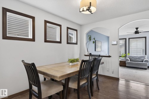 Dining area featuring wood-finish flooring, recessed windows with dark wood trim, and a contemporary ceiling light fixture - 108 Hewitt Circle, Spruce Grove, AB - Indoor Photo Showing Dining Room