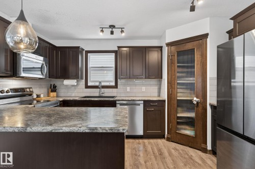 Kitchen featuring rich cabinetry with brushed nickel hardware, light-toned countertops, subway tile backsplash, and stainless steel appliances - 108 Hewitt Circle, Spruce Grove, AB - Indoor Photo Showing Kitchen With Upgraded Kitchen