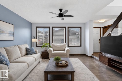 Open-concept living space featuring wood-finish flooring, a ceiling fan, and multiple windows with blinds - 108 Hewitt Circle, Spruce Grove, AB - Indoor Photo Showing Living Room