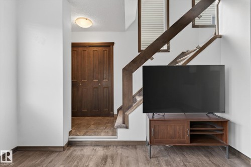 Wood-finish flooring throughout, featuring a staircase with wood railings and carpeted treads - 108 Hewitt Circle, Spruce Grove, AB - Indoor Photo Showing Other Room