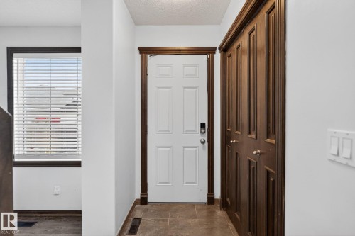 Entryway featuring a paneled door with dark wood-finish trim, tile flooring, and a window with blinds - 108 Hewitt Circle, Spruce Grove, AB - Indoor Photo Showing Other Room