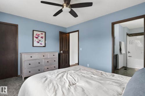 Bedroom featuring light blue walls, dark wood-finish trim, and textured gray carpeting - 108 Hewitt Circle, Spruce Grove, AB - Indoor Photo Showing Bedroom