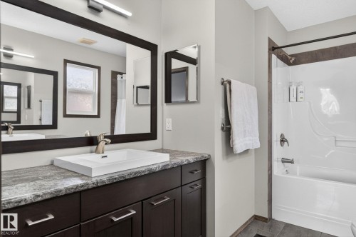Bathroom featuring a spacious vanity with a white rectangular sink, a brushed nickel faucet, and a large framed mirror - 108 Hewitt Circle, Spruce Grove, AB - Indoor Photo Showing Bathroom