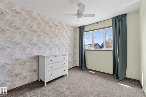 Bedroom featuring an accent wall with floral wallpaper, a multi-pane window, and a ceiling fan with integrated lighting - 108 Hewitt Circle, Spruce Grove, AB - Indoor