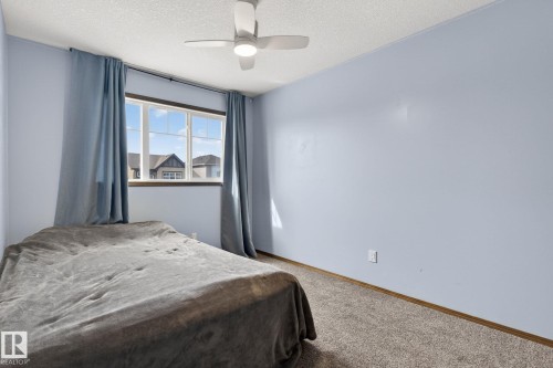 Light blue painted walls with textured carpeting, featuring a window with white framing and dark sills - 108 Hewitt Circle, Spruce Grove, AB - Indoor Photo Showing Bedroom