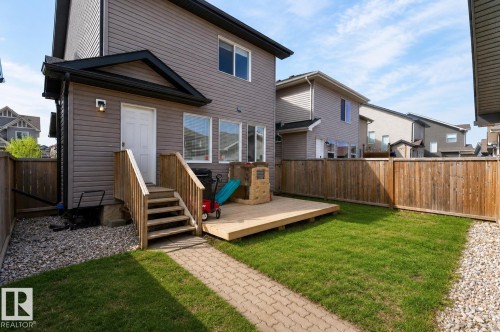 Fully fenced backyard featuring a wood deck, a paved walkway, a gravel border, and a green lawn - 108 Hewitt Circle, Spruce Grove, AB - Outdoor