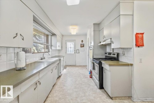 Galley kitchen with white cabinetry and view of the ravine - 9732 64 Street, Edmonton, AB - Indoor Photo Showing Kitchen