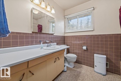 Bathroom featuring a light wood-finish vanity with an integrated sink and laminate countertop - 9732 64 Street, Edmonton, AB - Indoor Photo Showing Bathroom