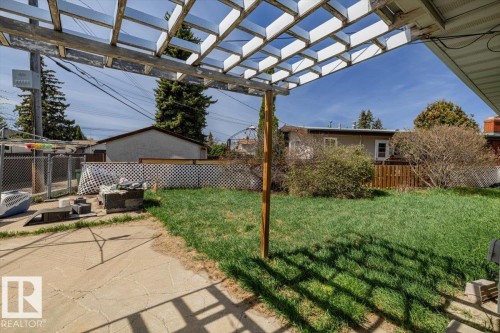 Soutwest facing backyard featuring a concrete patio, a wooden pergola, and a grassy expanse - 9732 64 Street, Edmonton, AB - Outdoor