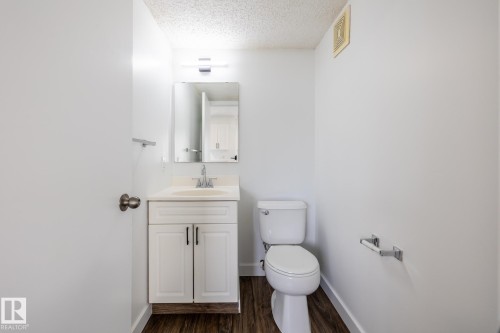 Bathroom featuring a white vanity with panel cabinetry, a light-toned countertop, and a chrome faucet - #136, 180 Bridgeport Bv, Leduc, AB - Indoor Photo Showing Bathroom