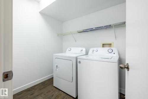Dedicated laundry area featuring white walls, durable wood-finish flooring, and a wire storage shelf - #136, 180 Bridgeport Bv, Leduc, AB - Indoor Photo Showing Laundry Room