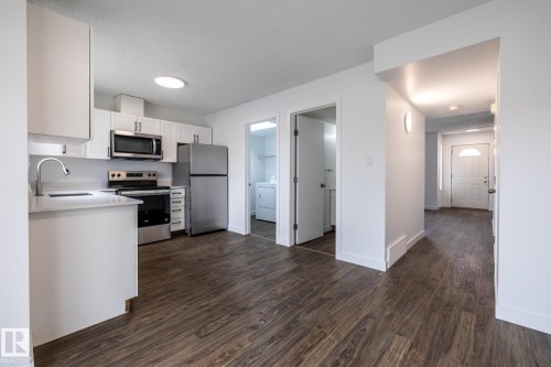 Contemporary kitchen featuring white cabinetry, stainless steel appliances, and a light-toned countertop - #136, 180 Bridgeport Bv, Leduc, AB - Indoor Photo Showing Kitchen