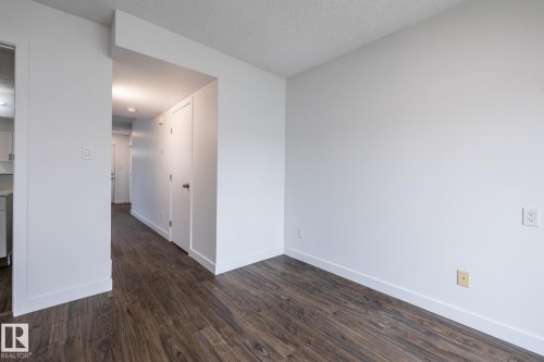 Open-concept living space featuring wood-finish flooring, white baseboards, and neutral wall tones - #136, 180 Bridgeport Bv, Leduc, AB - Indoor Photo Showing Other Room
