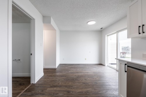 Open-concept living space with dark wood-finish flooring, white walls, and a recessed ceiling light - #136, 180 Bridgeport Bv, Leduc, AB - Indoor Photo Showing Other Room
