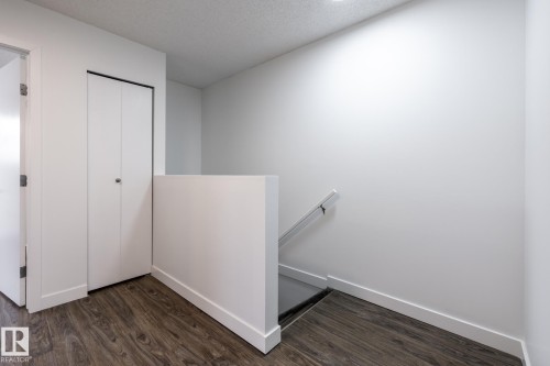 Hallway featuring wood-finish flooring, white walls, and a built-in bifold closet - #136, 180 Bridgeport Bv, Leduc, AB - Indoor Photo Showing Other Room