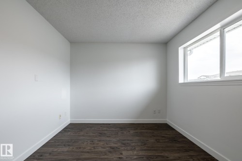 Light-filled room featuring white walls, dark wood-finish flooring, and white trim - #136, 180 Bridgeport Bv, Leduc, AB - Indoor Photo Showing Other Room