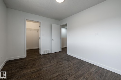 Interior room featuring dark wood-finish flooring, white walls, and bright overhead lighting - #136, 180 Bridgeport Bv, Leduc, AB - Indoor Photo Showing Other Room