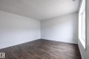 Spacious room featuring wood-finish flooring, crisp white walls, and a large window - #136, 180 Bridgeport Bv, Leduc, AB  - Indoor Photo Showing Other Room 