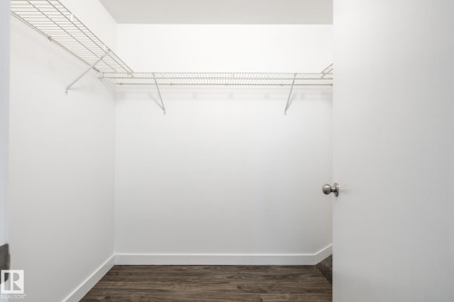 Walk-in closet featuring wire shelving, white painted walls, white baseboards, and wood-finish flooring - #136, 180 Bridgeport Bv, Leduc, AB - Indoor With Storage