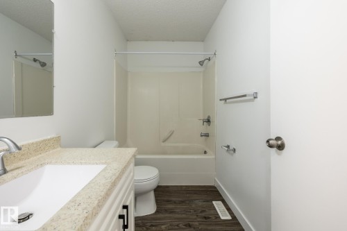 Bathroom featuring a vanity with an integrated sink and light-colored countertop, a toilet, and a combined tub and shower unit - #136, 180 Bridgeport Bv, Leduc, AB - Indoor Photo Showing Bathroom
