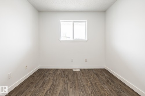 Room featuring wood-finish flooring, white baseboards, and bright white walls - #136, 180 Bridgeport Bv, Leduc, AB - Indoor Photo Showing Other Room