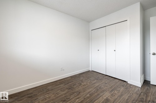 Room featuring wood-finish flooring, white walls, and a white bi-fold closet - #136, 180 Bridgeport Bv, Leduc, AB - Indoor Photo Showing Other Room