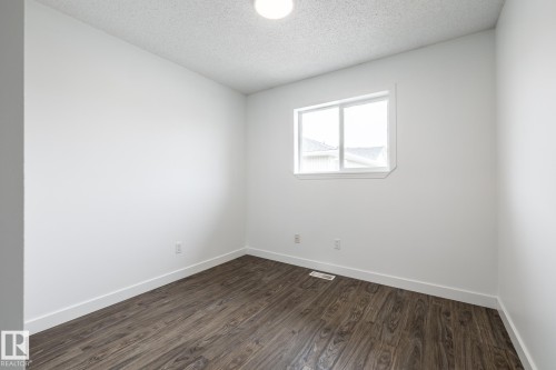 Bright room featuring wood-finish flooring, white walls, and a window with white trim - #136, 180 Bridgeport Bv, Leduc, AB - Indoor Photo Showing Other Room