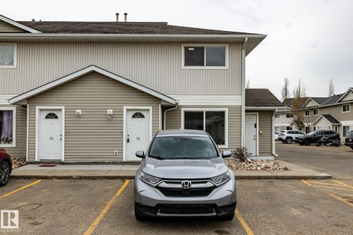 Multi-unit residential building featuring light-colored siding and a dark shingle roof - #136, 180 Bridgeport Bv, Leduc, AB - Outdoor