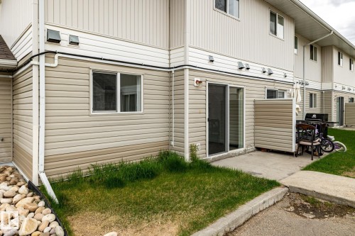 Rear exterior featuring neutral-toned horizontal siding, white trim, and a concrete patio - #136, 180 Bridgeport Bv, Leduc, AB - Outdoor