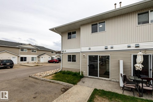Rear patio with concrete surface, sliding glass door access, and a partial grass area - #136, 180 Bridgeport Bv, Leduc, AB - Outdoor With Exterior