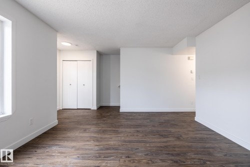 Open room featuring wood-finish flooring, white walls, and a window providing natural illumination - #136, 180 Bridgeport Bv, Leduc, AB - Indoor Photo Showing Other Room