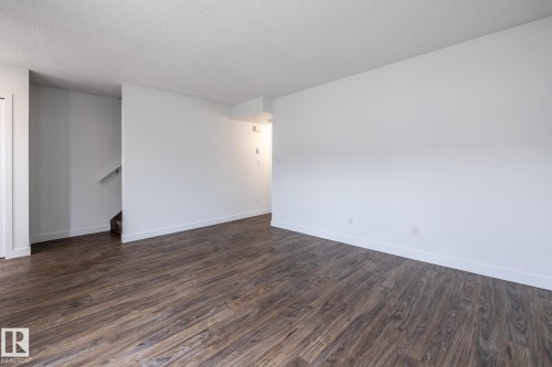 Spacious room featuring wood-finish flooring, white baseboards, and white walls - #136, 180 Bridgeport Bv, Leduc, AB - Indoor Photo Showing Other Room