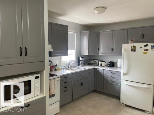 Kitchen featuring gray shaker-style cabinetry, white countertops, stainless steel sink, and light-toned flooring - 5339 52 Ave, Mundare, AB 