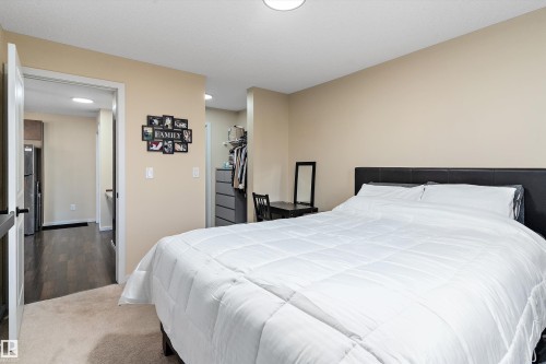 Carpeted bedroom featuring neutral wall tones and a black headboard - 122 3357 16A Avenue, Edmonton, AB - Indoor Photo Showing Bedroom