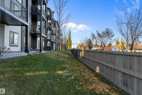 Multi-story residential building featuring balconies with black railings, horizontal siding, and a sloped grassy area - 122 3357 16A Avenue, Edmonton, AB - Outdoor