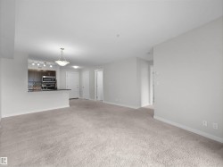 Open-concept living space featuring neutral carpeting and light-toned wall finishes - 