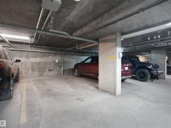 Concrete parking garage with exposed utility piping and fluorescent lighting - 