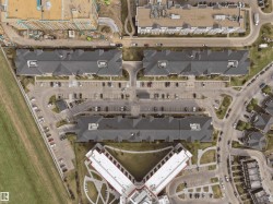 Aerial perspective showcasing multiple buildings with dark-pitched roofs, extensive surface parking areas, and surrounding roadways - 
