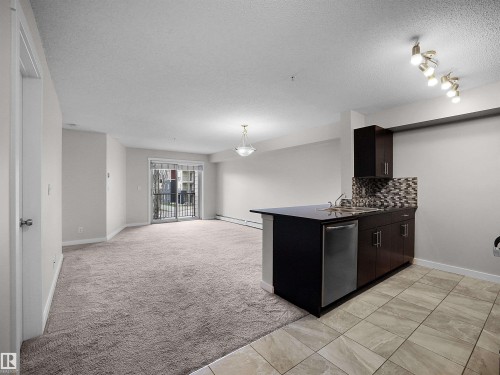 Kitchenette with dark wood-finish cabinetry, stainless steel dishwasher, and mosaic tile backsplash - 220 5804 Mullen Place, Edmonton, AB - Indoor Photo Showing Other Room