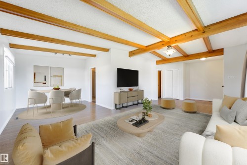 Spacious open-concept living area featuring exposed wood beams, light wood-finish flooring, white walls, and recessed lighting - 6134 37A Avenue, Edmonton, AB 