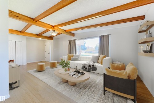 Spacious living area featuring exposed wood beam ceiling, wood-finish flooring, a large window, and built-in floating shelves - 6134 37A Avenue, Edmonton, AB 