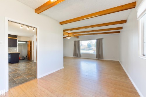 Spacious room featuring exposed wood ceiling beams, light wood-finish flooring, and multiple windows - 6134 37A Avenue, Edmonton, AB 