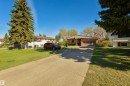 Single-story residence featuring brown siding, an attached garage with a brown door, and a paved driveway - 6134 37A Avenue, Edmonton, AB 
