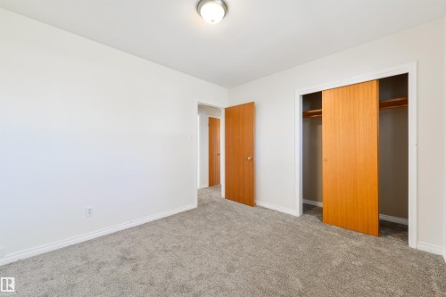 Bright interior space featuring light gray carpet flooring, white walls, and a ceiling-mounted light fixture - 6134 37A Avenue, Edmonton, AB 