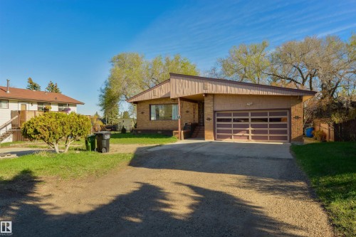 Single-story brick exterior featuring a multi-pane garage door, covered entryway, and asphalt driveway - 6134 37A Avenue, Edmonton, AB 